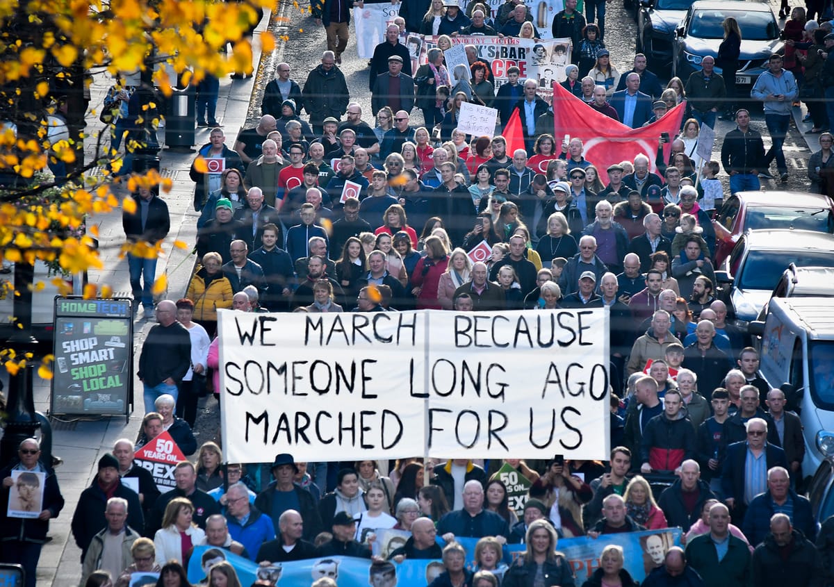 A street march carrying a sign reading, "We march because someone long ago marched for us." 